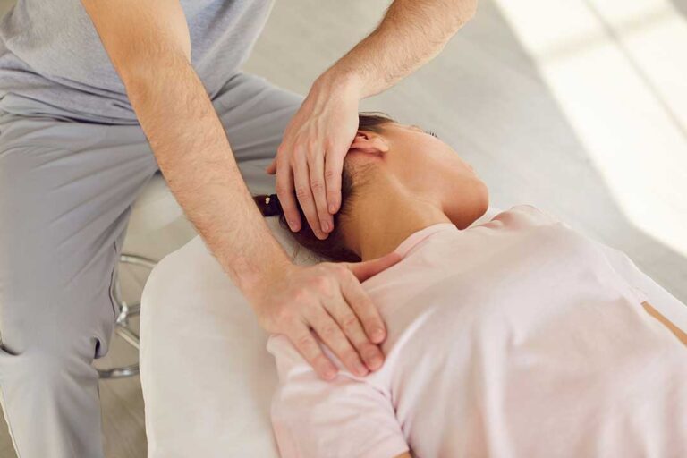 Person demonstrating a gentle shoulder stretch in a home living room with relaxed posture and neutral expression.