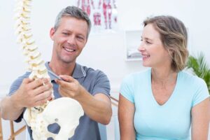 A chiropractor discussing x-ray results with a patient in a bright, comfortable office setting.
