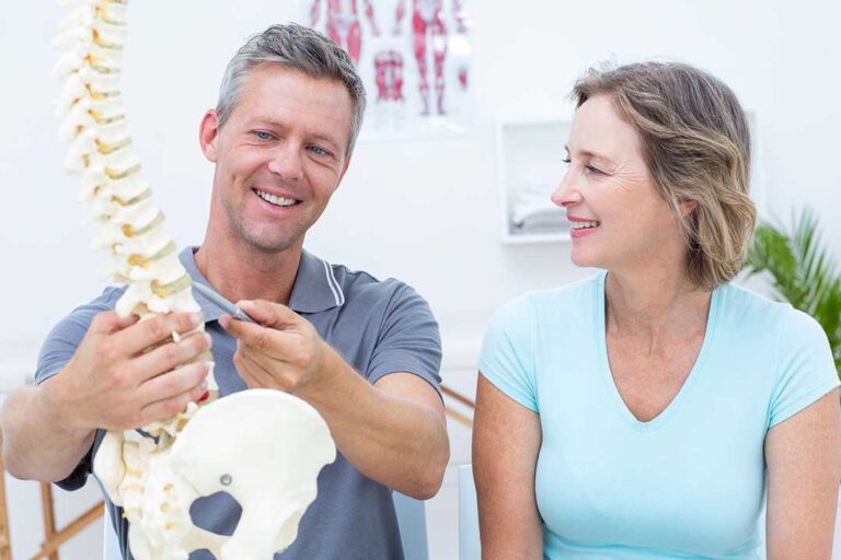 A chiropractor discussing x-ray results with a patient in a bright, comfortable office setting.